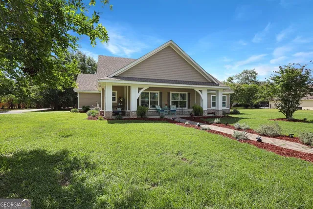 a view of house with a big yard potted plants and large tree