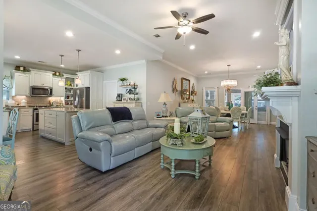 a living room with furniture kitchen view and a wooden floor
