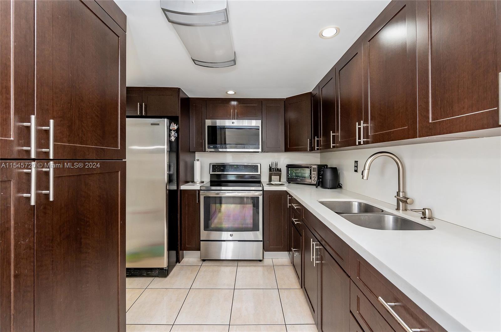 a kitchen with stainless steel appliances granite countertop a refrigerator a sink a stove and cabinets