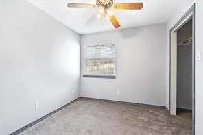 an empty room with a window and chandelier fan
