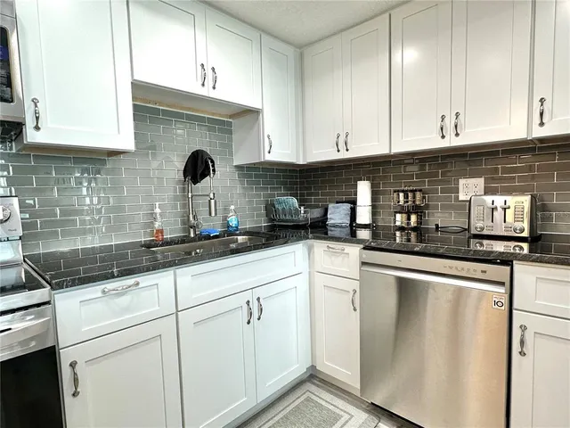 a kitchen with stainless steel appliances granite countertop a sink refrigerator and cabinets
