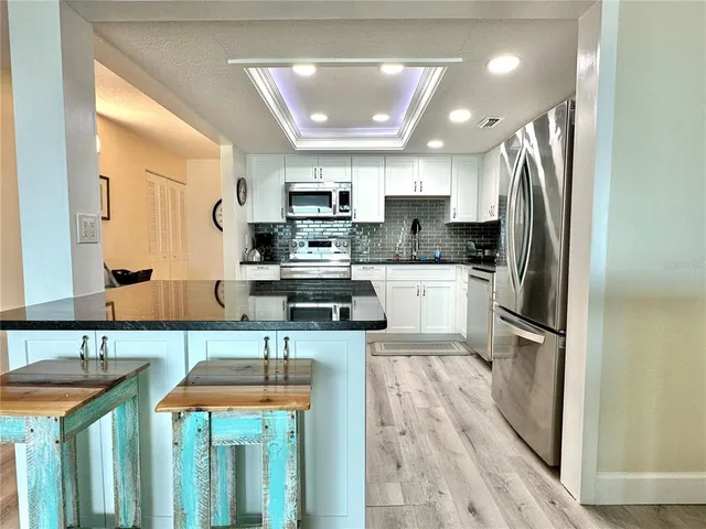 a view of a dining table chairs wooden floor and a kitchen