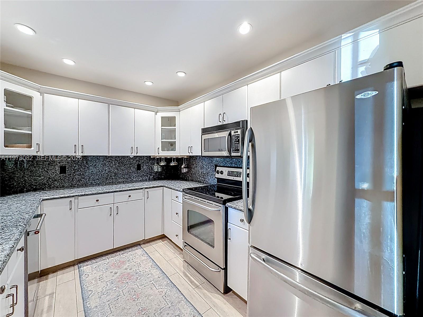 2128 Northeast 9th Avenue Wilton Manors, FL 33305 - Photo 7 of 34 a kitchen with stainless steel appliances granite countertop a refrigerator a sink and white cabinets