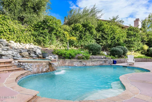 a view of a swimming pool with lawn chairs and plants