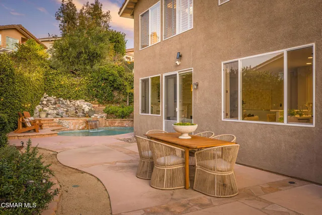 a patio with table and chairs and potted plants