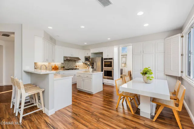 a kitchen with a table chairs stove and white cabinets