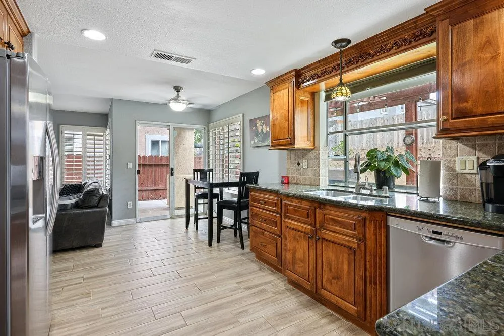 790 Mosaic Circle Oceanside, CA 92057 - Photo 23 of 47 a kitchen with stainless steel appliances granite countertop a sink dishwasher a stove and a refrigerator with wooden floor