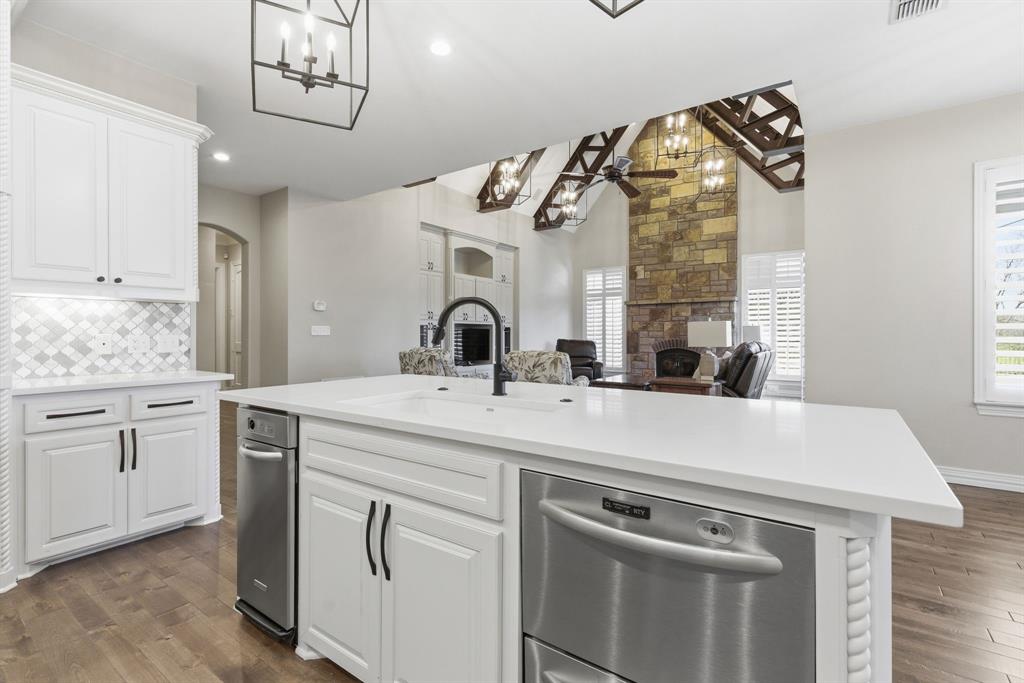 8970 Burnett Road Justin, TX 76247 - Photo 13 of 39 a kitchen with a sink dishwasher a stove and white cabinets with wooden floor