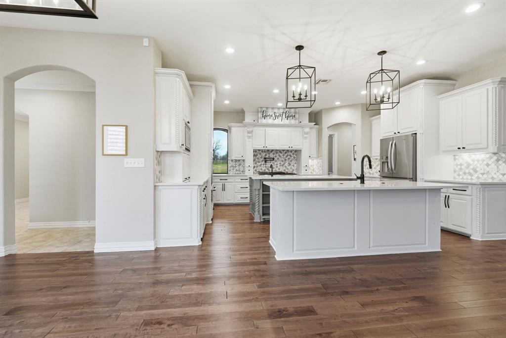 8970 Burnett Road Justin, TX 76247 - Photo 15 of 39 a large kitchen with stainless steel appliances kitchen island a refrigerator and a wooden floors