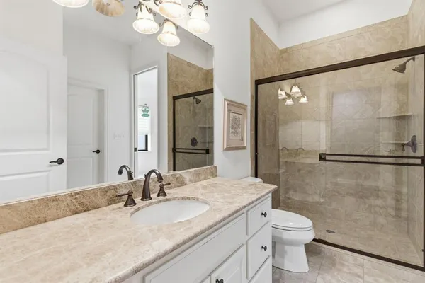 a bathroom with a granite countertop sink toilet a mirror and shower