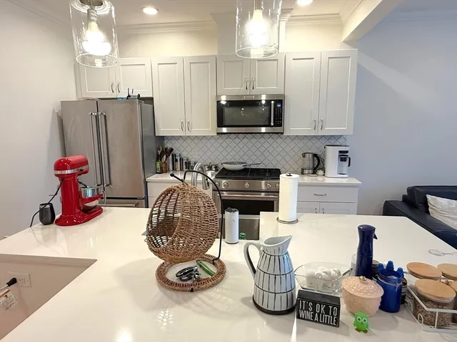 a kitchen with stainless steel appliances kitchen island granite countertop a sink dishwasher a microwave oven and a dining table with wooden floor