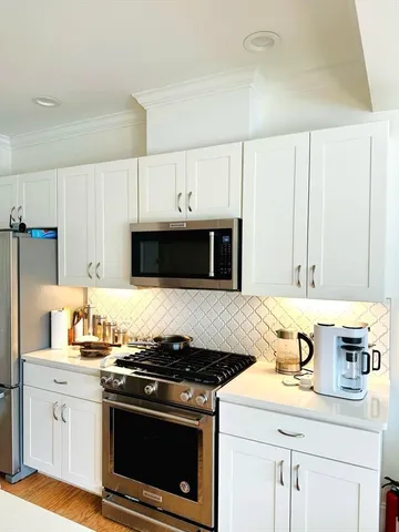 a kitchen with stainless steel appliances granite countertop a sink stove oven and white cabinets