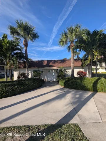 a front view of a house with a yard and palm trees