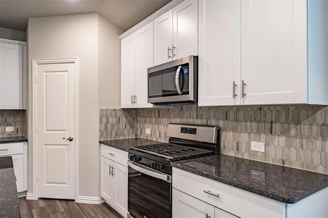 a kitchen with stainless steel appliances granite countertop a stove a microwave and a white cabinets