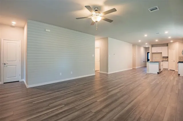 a view of a livingroom with a ceiling fan wooden floor and a ceiling fan