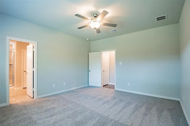 an empty room with closet and a ceiling fan