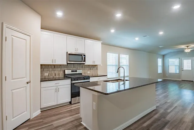 a kitchen with granite countertop a sink and white cabinets