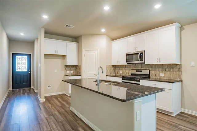a kitchen with granite countertop a sink stove and refrigerator