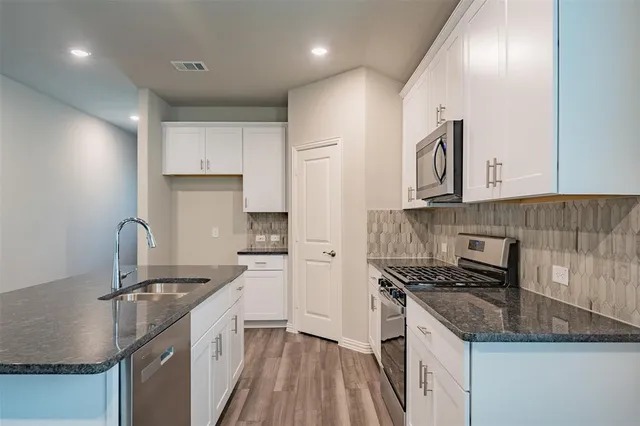 a kitchen with kitchen island granite countertop a sink stainless steel appliances and cabinets