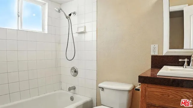 a bathroom with a granite countertop bathtub sink vanity and toilet
