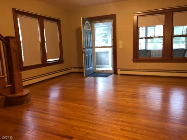 a view of an empty room with wooden floor and a window