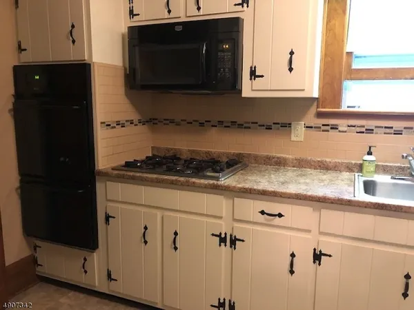 a kitchen with granite countertop white cabinets and black appliances