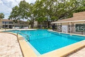 a view of a swimming pool with a bench and trees around