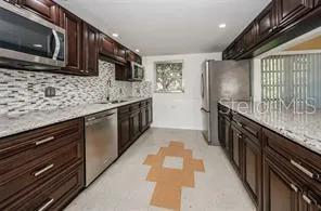 a kitchen with stainless steel appliances granite countertop a sink stove microwave refrigerator and wooden cabinets