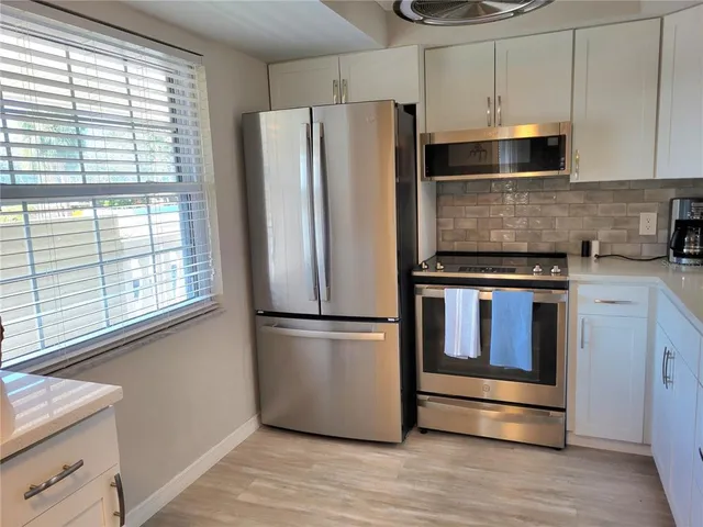 a kitchen with stainless steel appliances a refrigerator and a window
