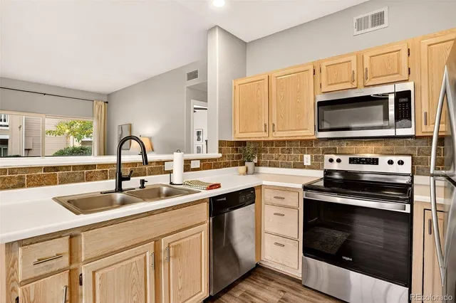 a kitchen with granite countertop a sink stainless steel appliances and cabinets