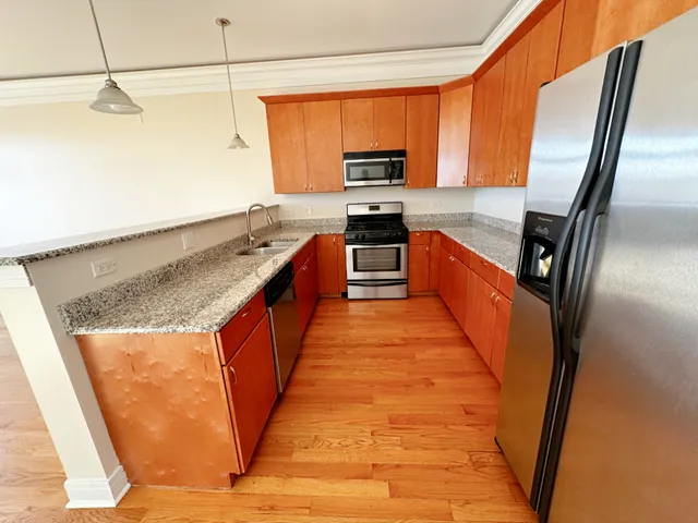 a large kitchen with stainless steel appliances granite countertop a refrigerator a stove top oven a sink and dishwasher