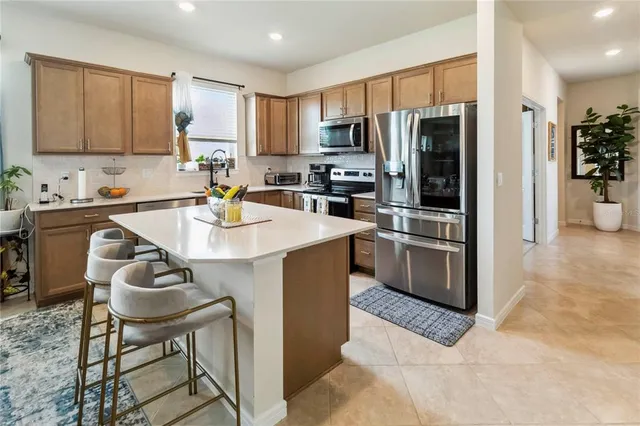 a kitchen with stainless steel appliances granite countertop a stove a refrigerator a sink a dining table and chairs