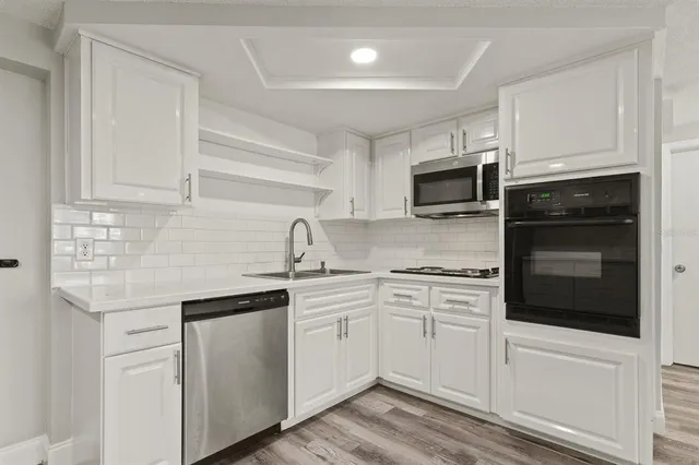 a kitchen with stainless steel appliances granite countertop white cabinets a sink and dishwasher