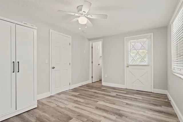 a view of empty room with wooden floor and fan