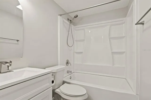 a bathroom with a granite countertop bathtub shower sink vanity and toilet