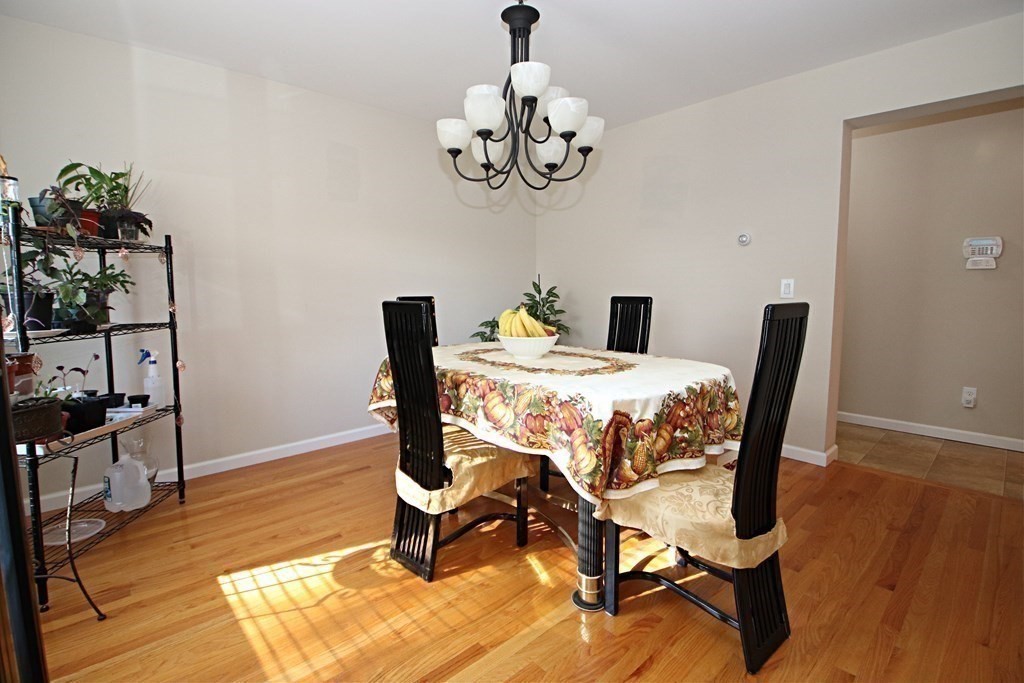 10 Pace Road Saugus, MA 01906 - Photo 16 of 42 a dining room with wooden floor a chandelier a wooden table and chairs