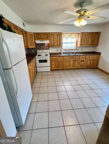 a kitchen with granite countertop a refrigerator and a stove top oven