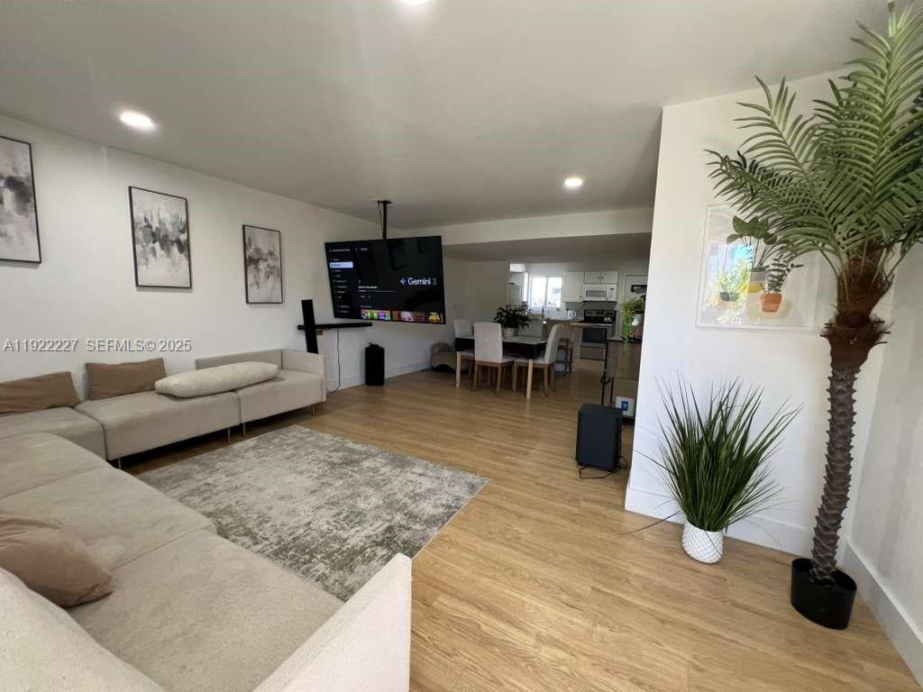 a living room with furniture hard wood floor and a flat screen tv