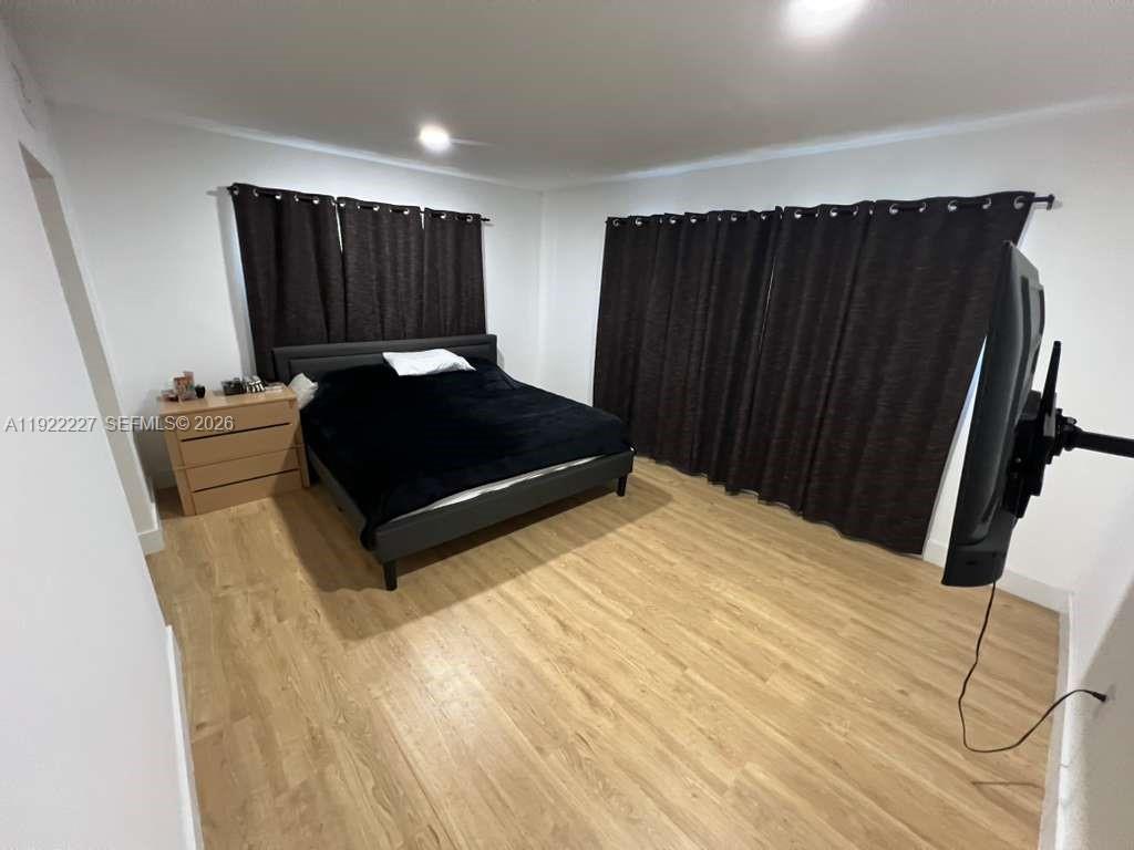 1480 Northeast 151st Street, Unit 101 Miami, FL 33162 - Photo 21 of 26 a bed sitting in a bedroom next to a cabinet