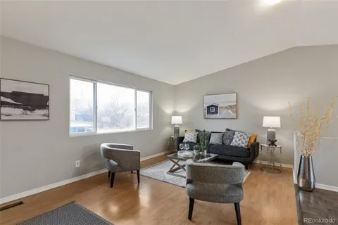 a living room with furniture a refrigerator and a dining table with wooden floor