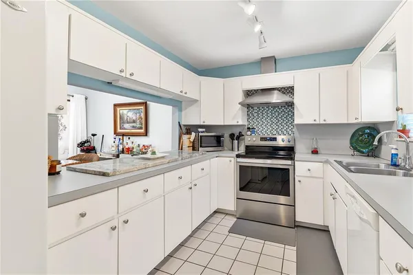 a kitchen with stainless steel appliances white cabinets a window and a sink