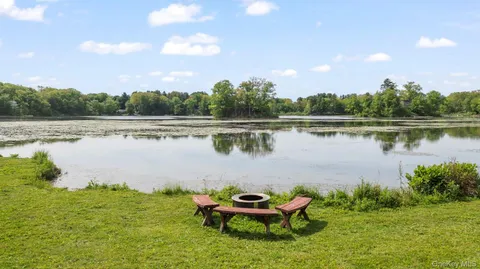 a lake view with a bench and trees in the background