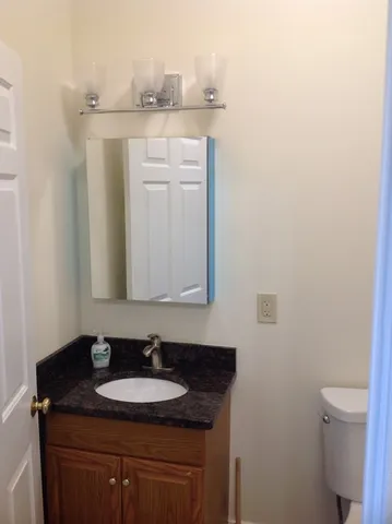 a bathroom with a granite countertop sink and a toilet