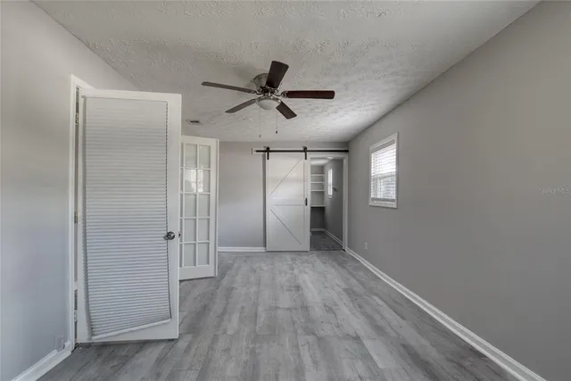 a view of empty room with wooden floor and ceiling fan