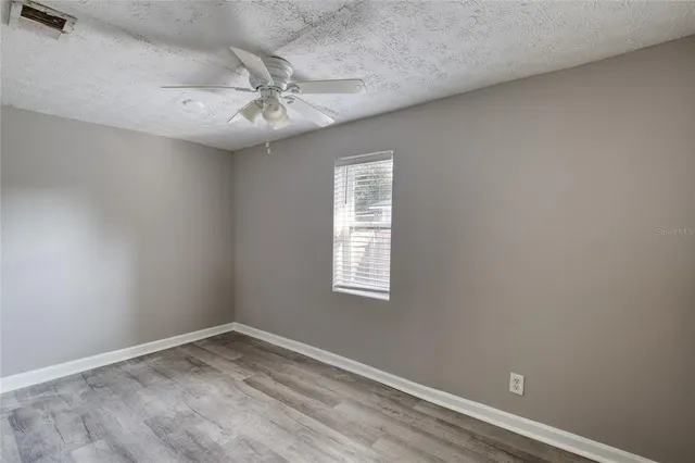 an empty room with a window and a fan
