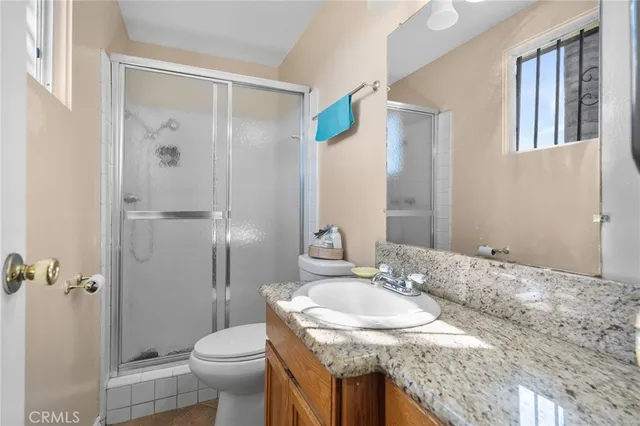 a bathroom with a granite countertop sink toilet and shower