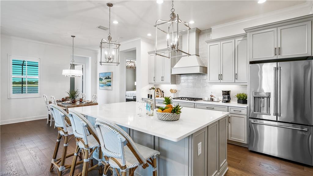 3992 Skysail Drive Naples, FL 34120 - Photo 6 of 12 a kitchen with a refrigerator a stove a sink dishwasher and white cabinets with wooden floor