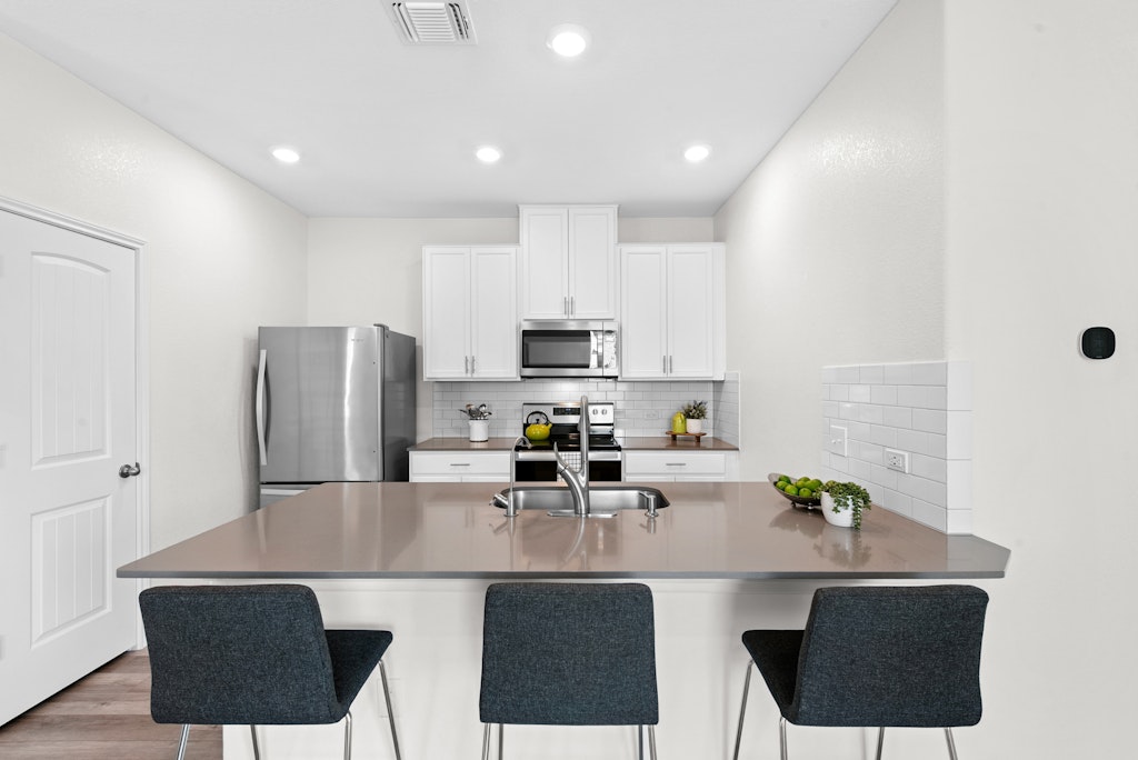 438 Thunder Valley Trail Georgetown, TX 78626 - Photo 2 of 21 a kitchen with stainless steel appliances granite countertop a dining table chairs refrigerator and microwave