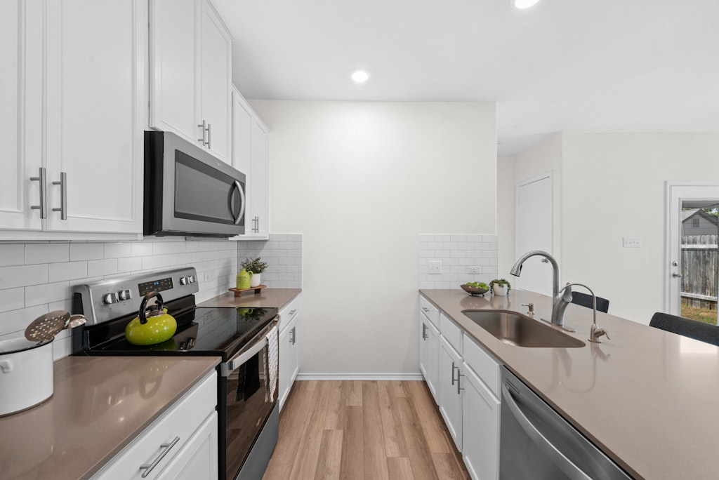 438 Thunder Valley Trail Georgetown, TX 78626 - Photo 6 of 21 a kitchen with stainless steel appliances granite countertop a sink a stove top oven a counter space and cabinets