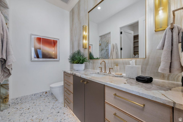 2867 East Granite Way St. George, UT 84790 - Photo 45 of 69 Bathroom featuring a floating vanity with a stone countertop, an undermount sink, and brass hardware